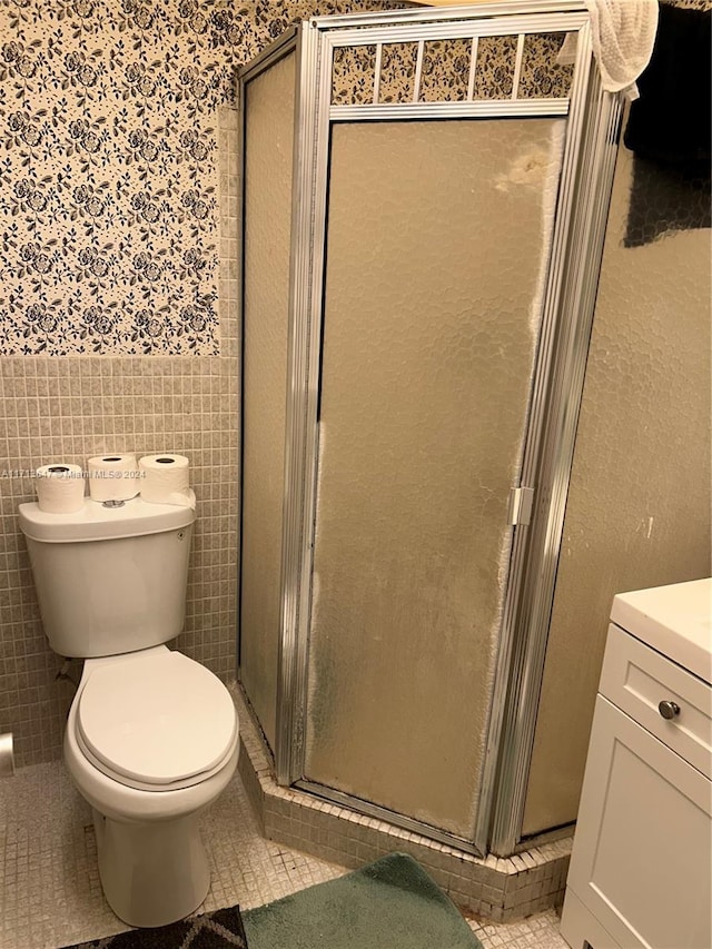 bathroom featuring tile patterned flooring, toilet, tile walls, and a shower with shower door