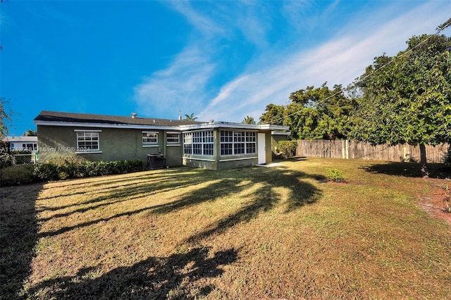 rear view of property featuring a yard and central AC