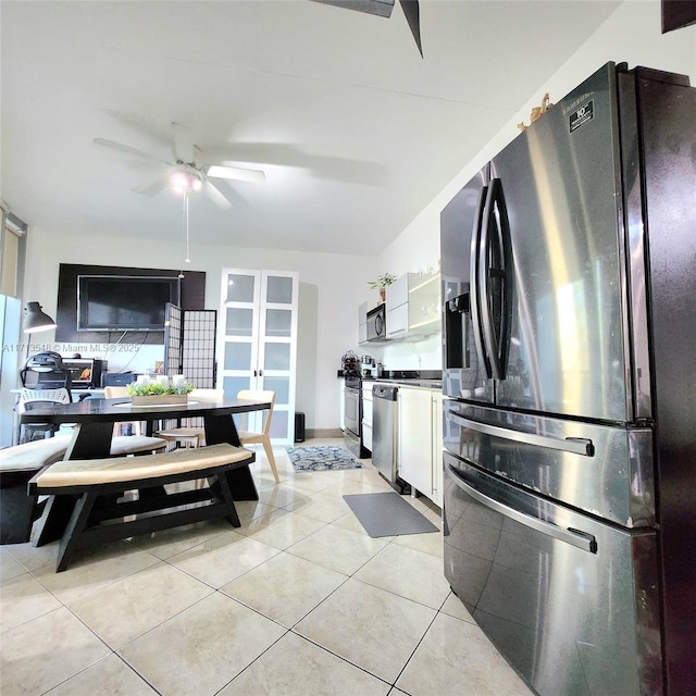 kitchen with light tile patterned floors, stainless steel appliances, white cabinets, ceiling fan, and exhaust hood