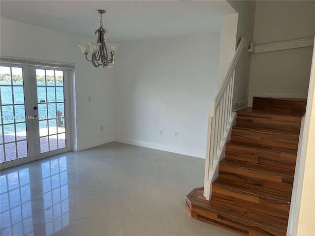 stairway featuring tile patterned floors, french doors, a water view, and a chandelier