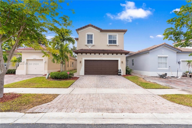 mediterranean / spanish-style home featuring a front lawn and a garage