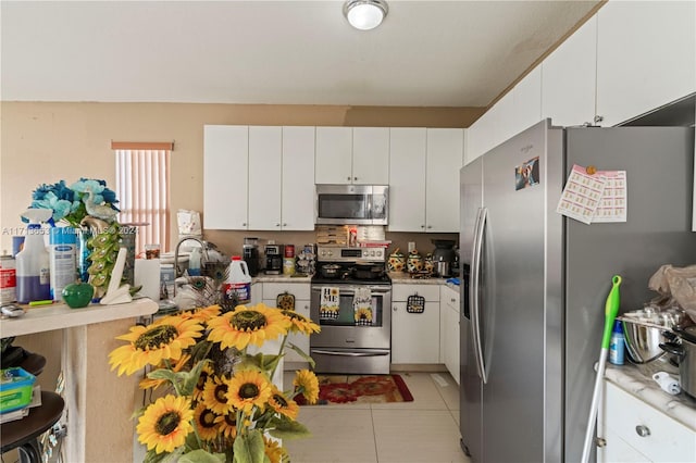 kitchen with appliances with stainless steel finishes, white cabinetry, and light tile patterned flooring