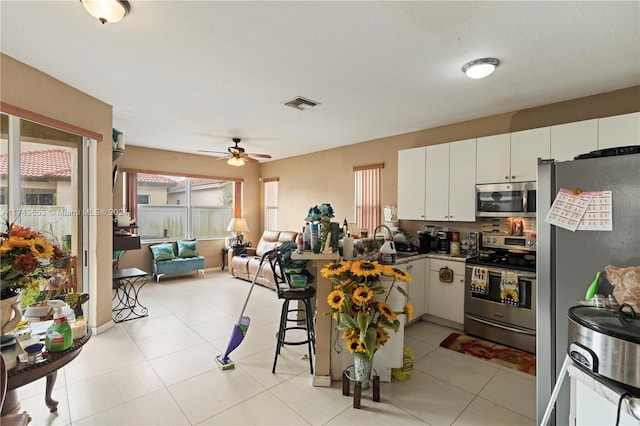 kitchen featuring white cabinetry, ceiling fan, kitchen peninsula, a breakfast bar area, and appliances with stainless steel finishes