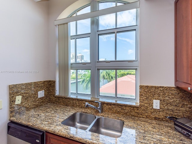 kitchen featuring decorative backsplash, sink, stainless steel dishwasher, and stone countertops