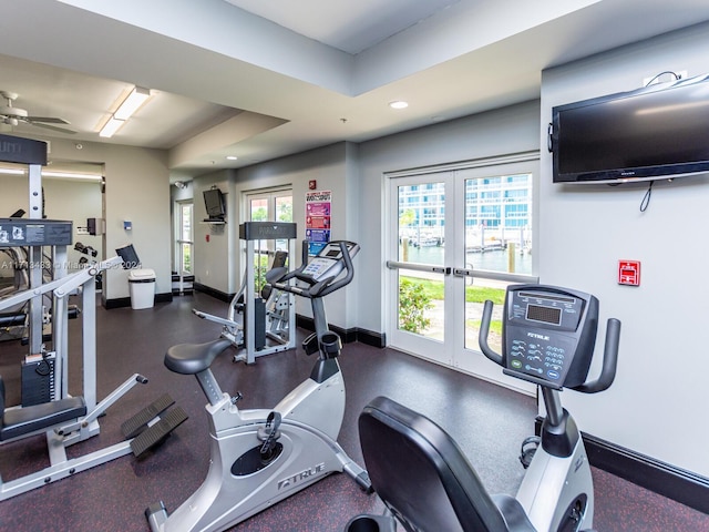 exercise room featuring a tray ceiling and ceiling fan