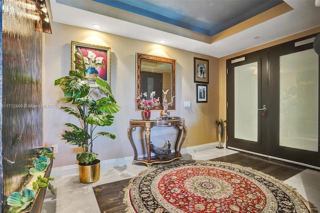 entrance foyer with a tray ceiling and french doors