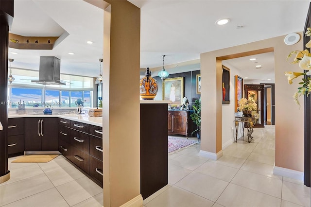 kitchen with light tile patterned flooring, island range hood, decorative light fixtures, and dark brown cabinets