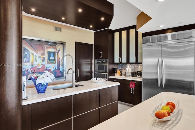 kitchen featuring appliances with stainless steel finishes, sink, dark brown cabinets, and decorative backsplash