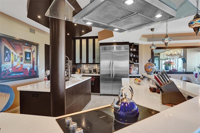 kitchen featuring light tile patterned floors, premium range hood, hanging light fixtures, a center island, and built in fridge