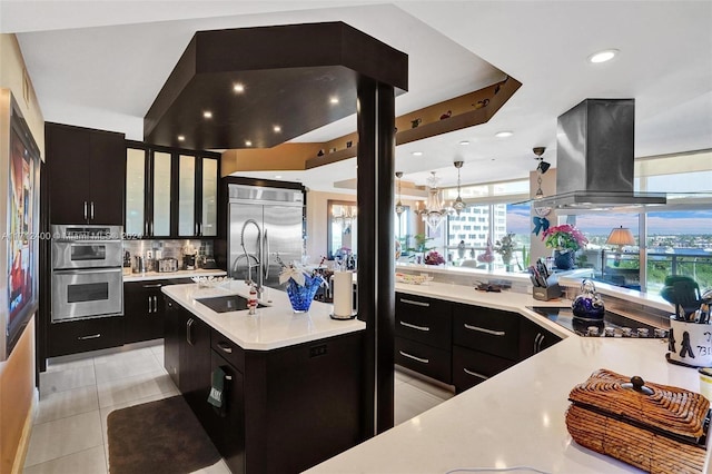 kitchen featuring sink, light tile patterned floors, island exhaust hood, stainless steel appliances, and a kitchen island with sink