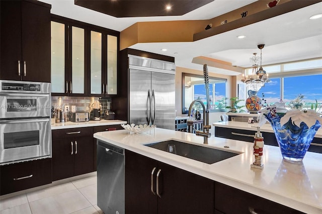 kitchen with light tile patterned flooring, sink, decorative light fixtures, a notable chandelier, and stainless steel appliances