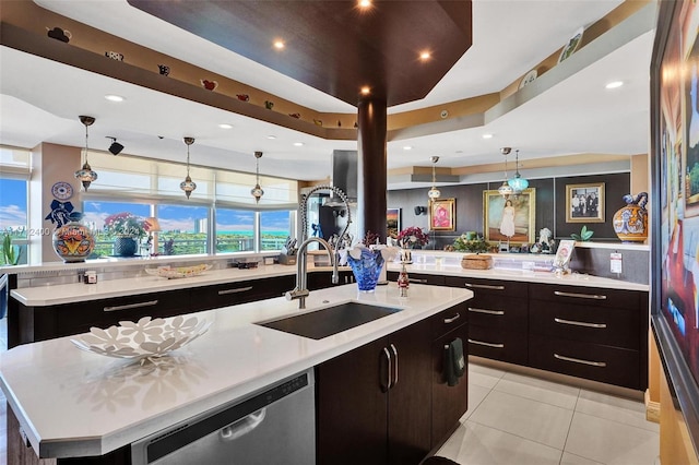 kitchen featuring decorative light fixtures, dishwasher, sink, and a large island with sink