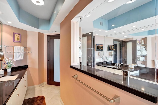 kitchen with white cabinetry, a raised ceiling, sink, and light tile patterned floors