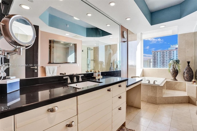 bathroom featuring tile patterned flooring, vanity, and tiled bath