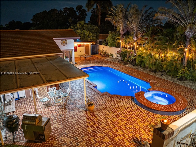 pool at twilight featuring a patio, area for grilling, and a pool with connected hot tub