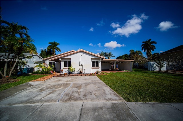 view of front of house with an attached carport, driveway, a front yard, and stucco siding