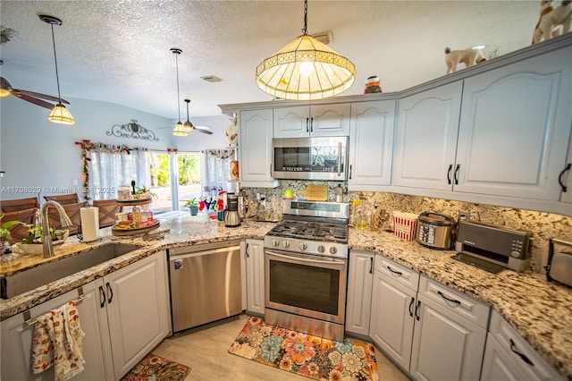 kitchen featuring ceiling fan, a sink, appliances with stainless steel finishes, pendant lighting, and backsplash