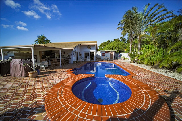 view of pool featuring an outbuilding, outdoor dining space, a pool with connected hot tub, a patio, and fence