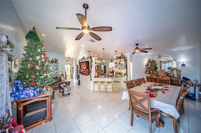 dining space with light tile patterned floors, visible vents, a textured ceiling, and a ceiling fan