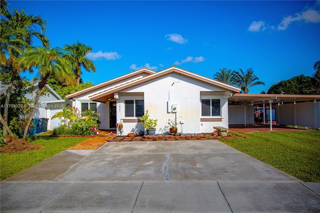 view of front facade with a carport, stucco siding, concrete driveway, and a front yard