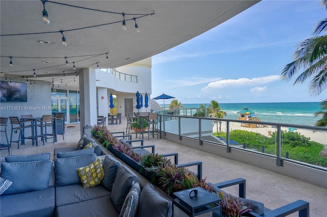 view of patio featuring a balcony, a water view, an outdoor hangout area, and a view of the beach