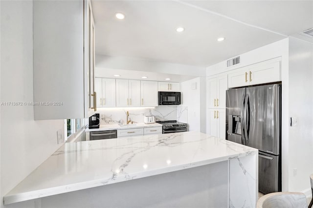 kitchen featuring kitchen peninsula, light stone countertops, white cabinets, and appliances with stainless steel finishes