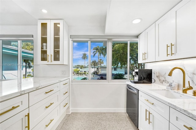 kitchen featuring stainless steel dishwasher, light stone countertops, white cabinetry, and sink