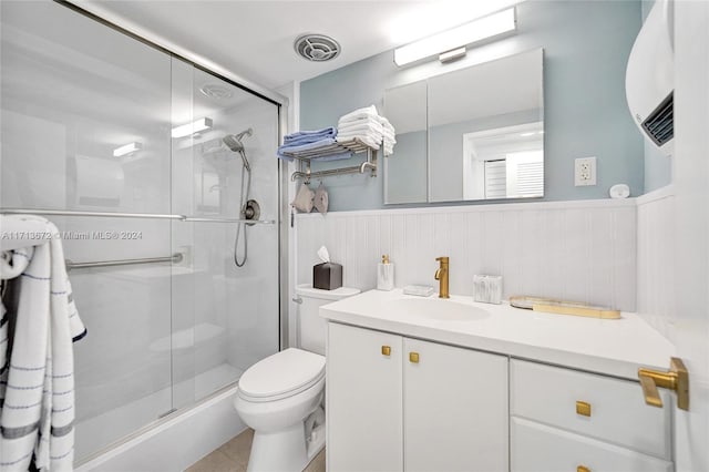 bathroom featuring tile patterned floors, vanity, a shower with shower door, and toilet