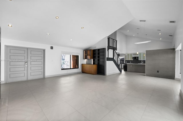 unfurnished living room with sink and high vaulted ceiling