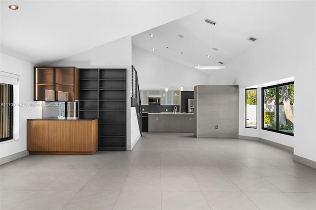 kitchen featuring tasteful backsplash, high vaulted ceiling, hanging light fixtures, and sink