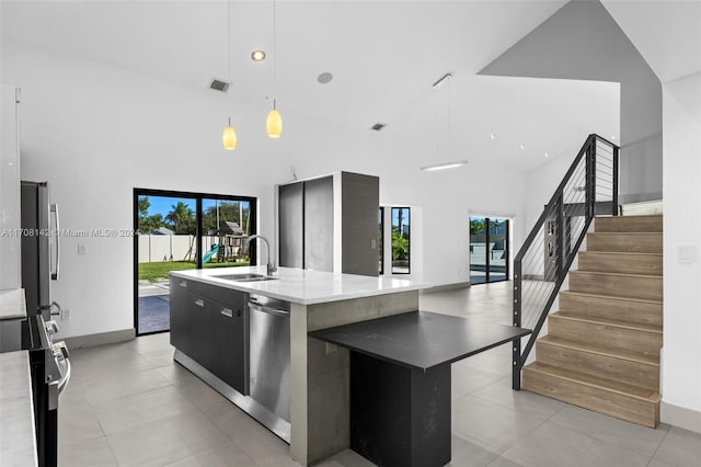 kitchen with sink, stainless steel dishwasher, a towering ceiling, pendant lighting, and a center island with sink