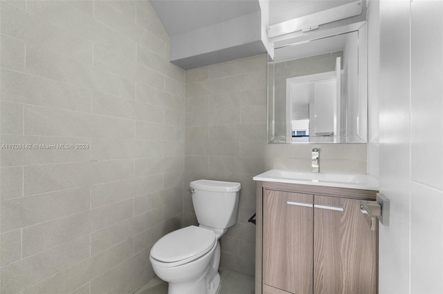 bathroom with vanity, toilet, and tile walls