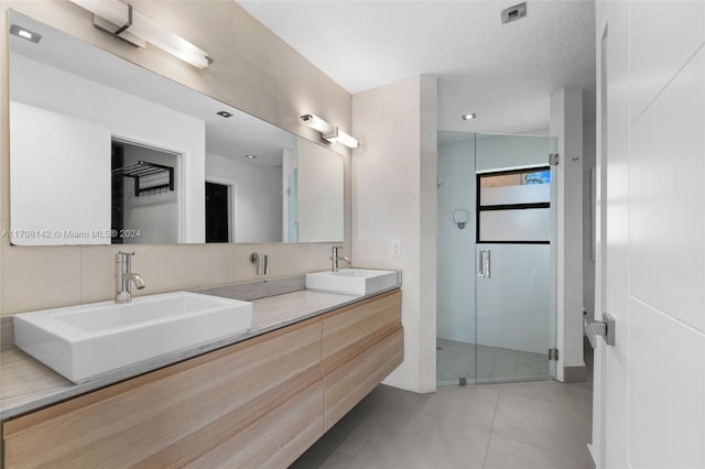 bathroom featuring a textured ceiling, vanity, tile patterned floors, and walk in shower