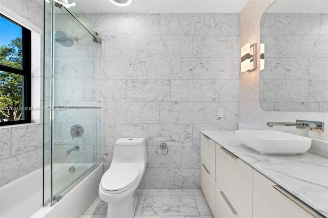 full bathroom with shower / bath combination with glass door, vanity, tile walls, and toilet