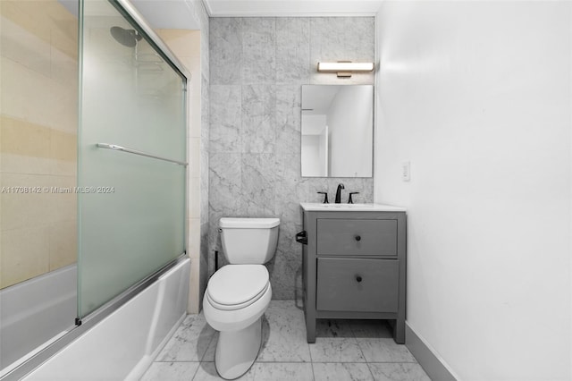 full bathroom with vanity, toilet, shower / bath combination with glass door, and tile walls