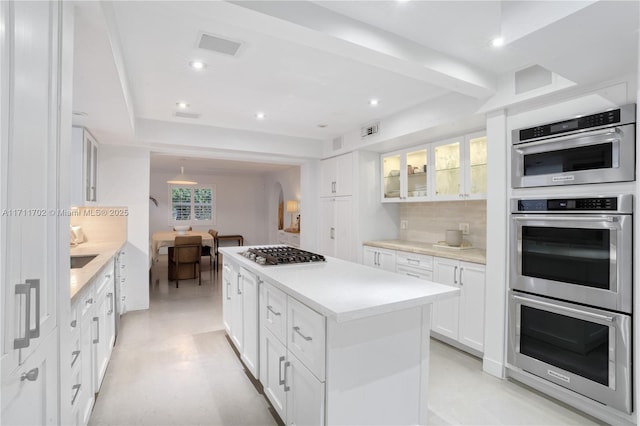 kitchen with tasteful backsplash, a center island, plenty of natural light, stainless steel appliances, and white cabinets