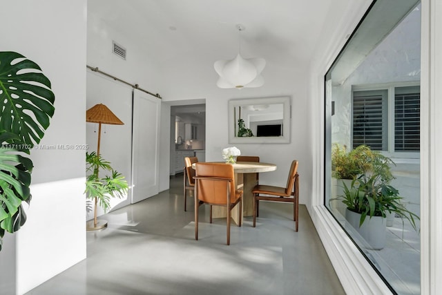 dining area with concrete floors and a barn door