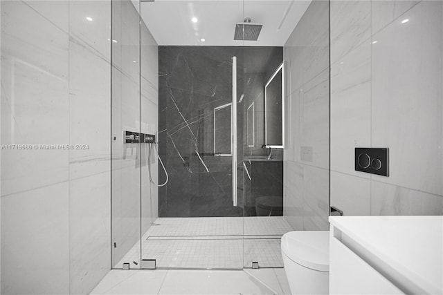 bathroom with tile patterned flooring, toilet, a shower with shower door, and tile walls