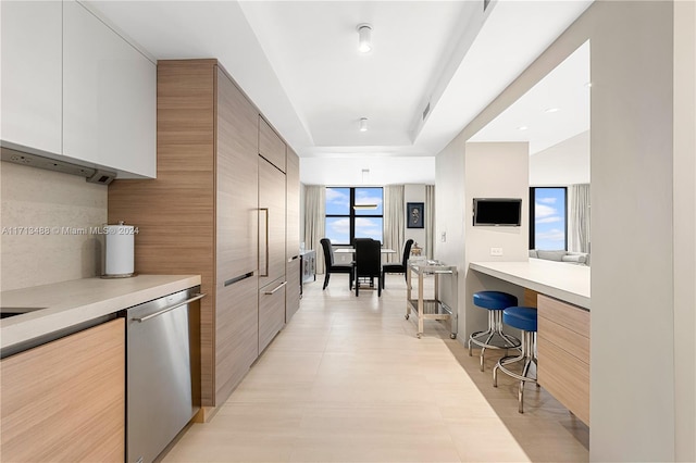 kitchen featuring white cabinets, a kitchen breakfast bar, tasteful backsplash, and stainless steel dishwasher