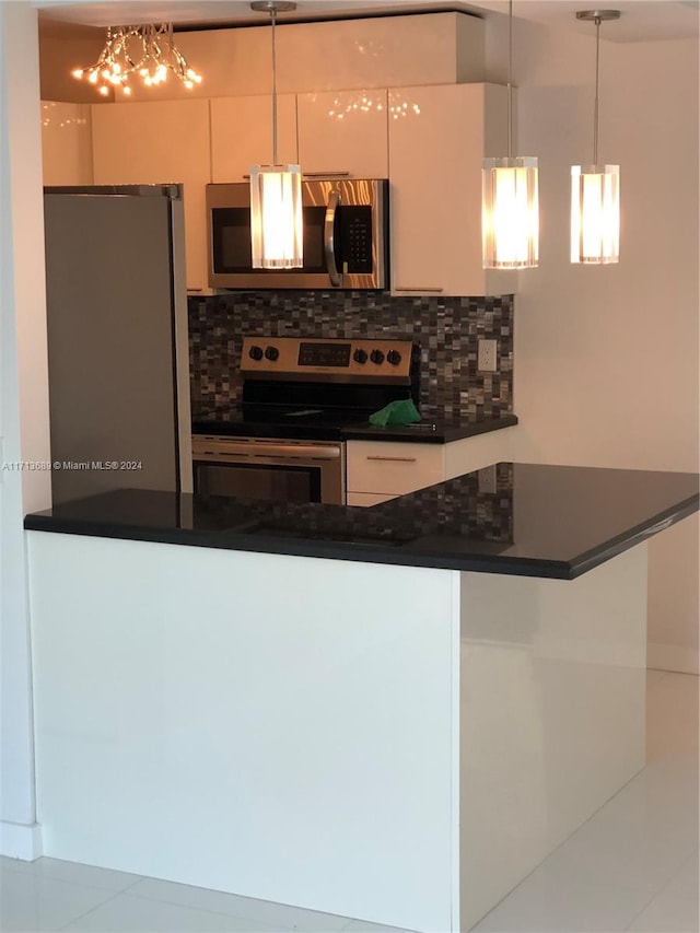 kitchen with backsplash, white cabinets, stainless steel appliances, and decorative light fixtures