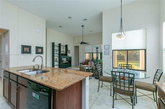 kitchen featuring pendant lighting, dishwasher, sink, a kitchen island with sink, and light stone countertops