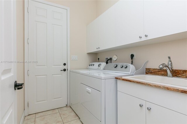 laundry room with light tile patterned flooring, cabinets, washer and clothes dryer, and sink