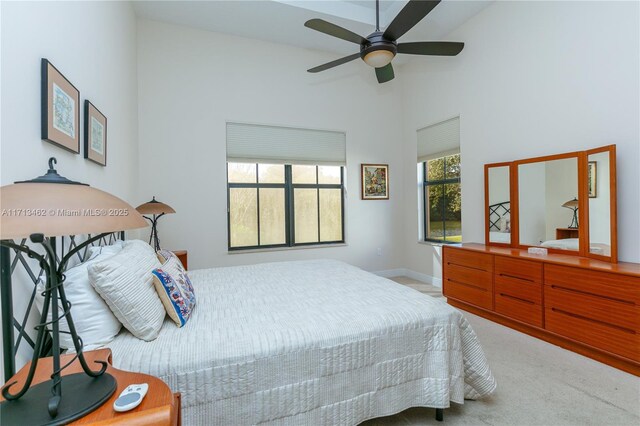 bedroom with ceiling fan, high vaulted ceiling, and light colored carpet