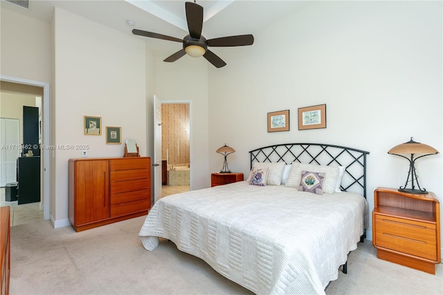 bedroom with connected bathroom, light colored carpet, ceiling fan, and a high ceiling