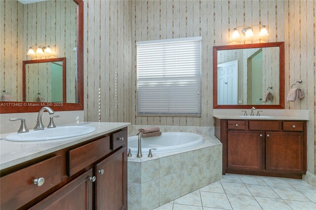 bathroom featuring tiled tub, vanity, and tile patterned floors