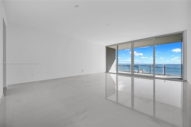 tiled spare room with a water view and expansive windows