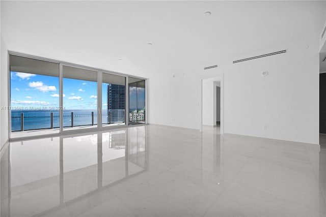 tiled empty room with a water view and a wall of windows