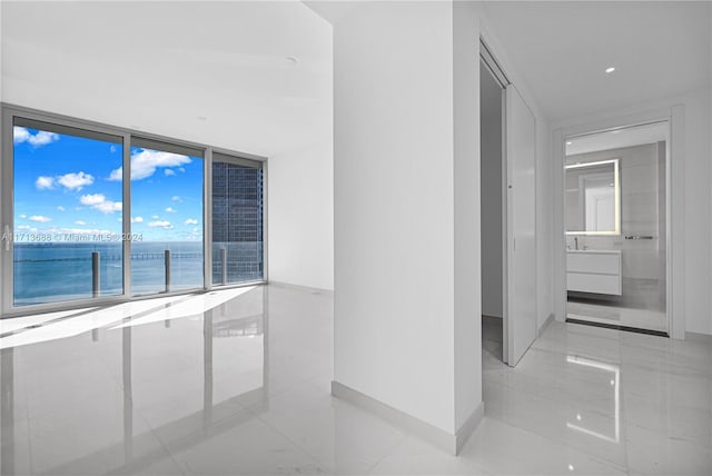 hall featuring floor to ceiling windows, a water view, and light tile patterned floors