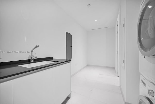 laundry room featuring sink and stacked washer and clothes dryer