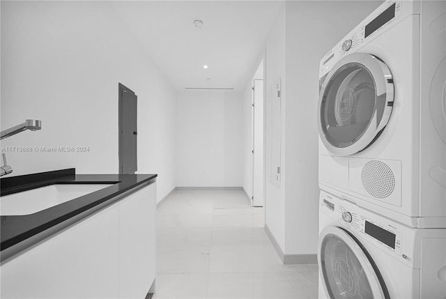 laundry room with stacked washer and dryer, light tile patterned floors, and sink